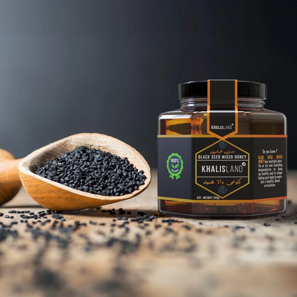 A jar of Khalisland Black Seed Honey with a metal lid, placed next to a wooden bowl filled with black seeds on a dark background.