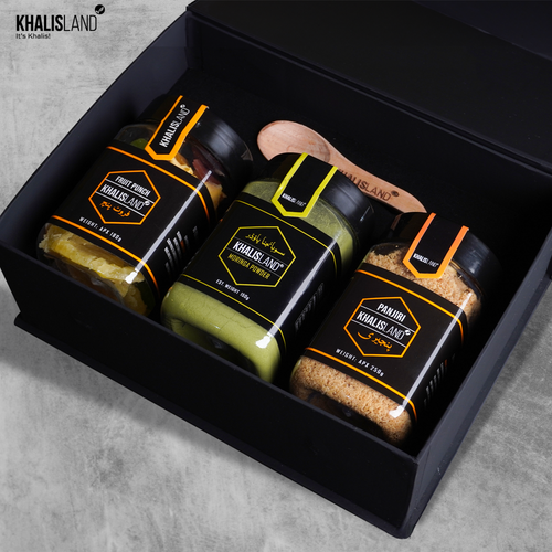 A set of three KhalisLand branded jars of food items, including Fruit Punch Sweetness, Gurr Panjeeri, and Magical Moringa Powder, presented in a black box with each jar clearly labeled.